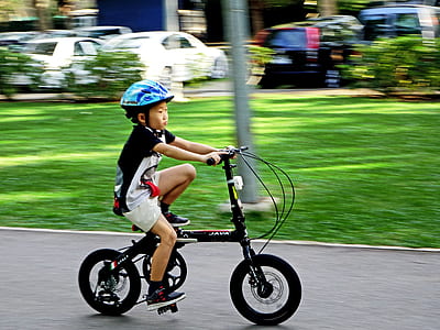 boy riding on black bicycle near parked vehicles at daytime thumbnail