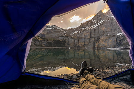 person laying inside of tent in front of body of water thumbnail