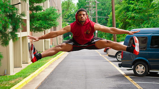 Man Jumping at the Pathway Beside Parking Lot thumbnail