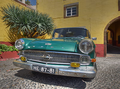 vintage green car parked in front of yellow building during daytime thumbnail