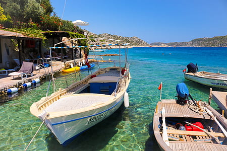 white and blue boat on water near the dock at daytime thumbnail