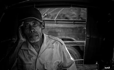 grayscale photo of man holding his head near window thumbnail