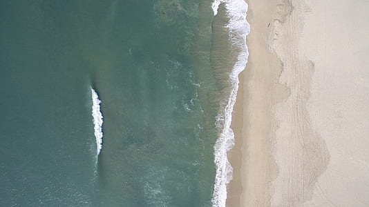 aerial photography of ocean water and beach sand thumbnail
