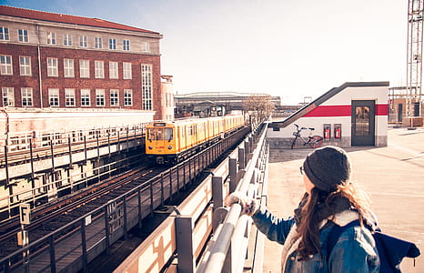 woman holding on gray bar looking at yellow train thumbnail