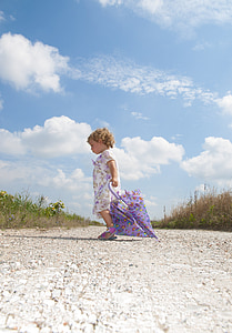 toddler holding umbrella between grass field under cumulus clouds thumbnail