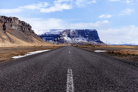 gray asphalt surrounded with sand and mountains thumbnail