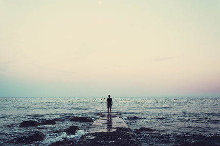 man standing on wooden dock in the middle of body of water thumbnail