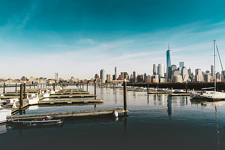 white sail boat near pier and freedom tower photo thumbnail