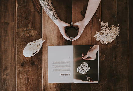 person holding mug between skull and flower thumbnail