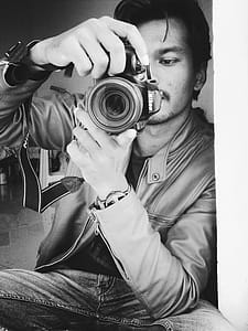Monochrome Photography of Man Holding Black Nikon Camera thumbnail