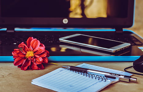 White Smartphone on Black Laptop Next to Pen on White Notepad thumbnail