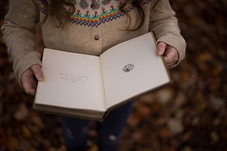 shallow focus photography of person holding book thumbnail