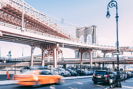 orange car near black SUV and bridge thumbnail