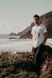 man standing on cliff near ocean thumbnail