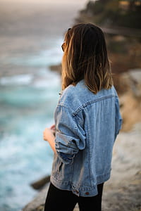 woman standing on cliff looking on sea taken at daytime thumbnail