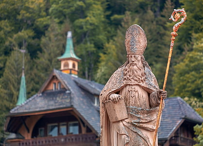 selective focus photography of bishop statue near house thumbnail
