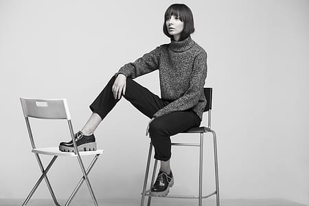 grayscale photo of women sitting on metal bar stool thumbnail