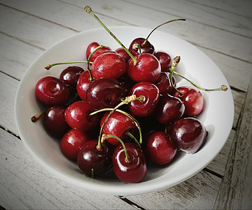 closeup photography of Cherries in white ceramic bowl on white wooden table thumbnail