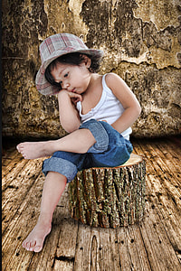 girl in white spaghetti strap shirt and blue denim jeans sits of brown tree log thumbnail