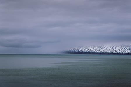 long exposure photography of body of water near mountain thumbnail