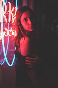 woman leaning on neon signage during night time thumbnail