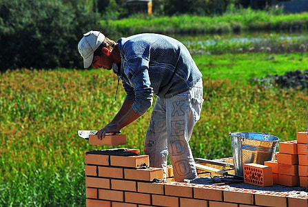 man placing brown bricks during daytime thumbnail