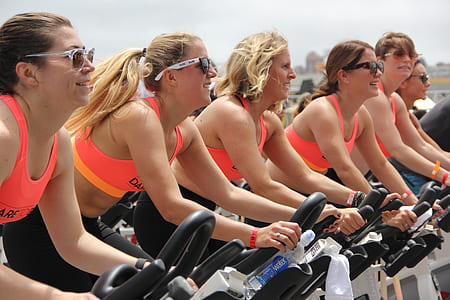 five women in pink sports bra on stationary bike thumbnail