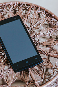Black smartphone on a miniature brown table thumbnail