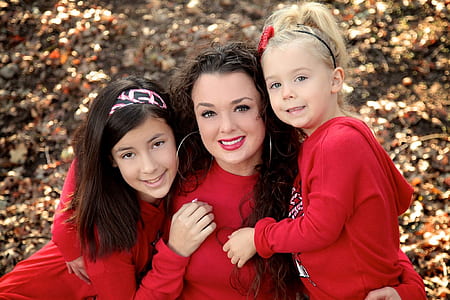 woman and two girls on front of brown trees thumbnail