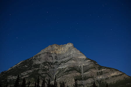 grey and black mountain under blue star filled nighttime sky thumbnail