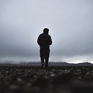 man walking on pebbles with mountain in distance thumbnail
