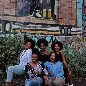 group of five friends sitting near wall thumbnail