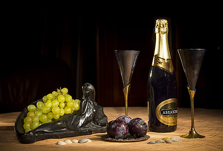 wine bottle and martini glasses beside green grapes thumbnail