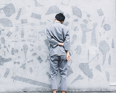 man standing near white concrete wall thumbnail