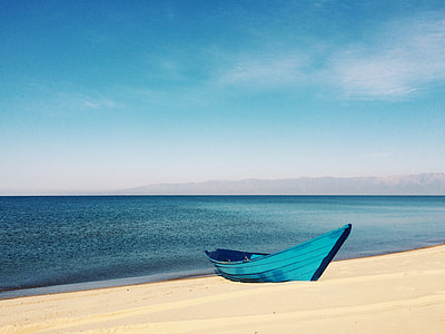 blue canoe boat on seashore near bodies of water thumbnail