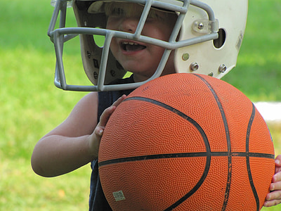 smiling child holding ball wearing white football helmet thumbnail
