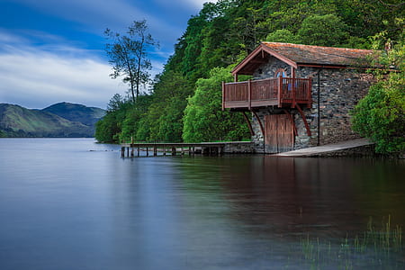 brown wooden house near body of water during daytime thumbnail