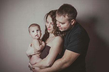 man and woman hugging toddler near wall thumbnail