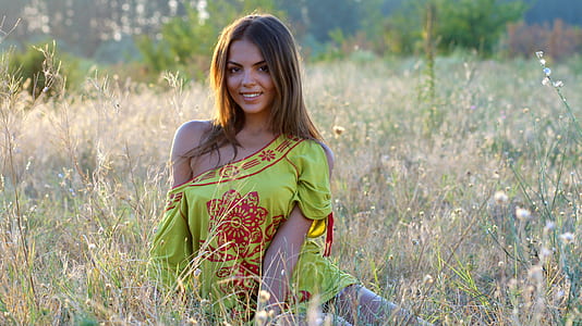 Woman Wearing Yellow and Red Dress Sitting on the Ground While Looking at the Camera thumbnail