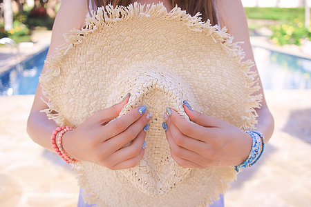 woman holding brown summer hat thumbnail