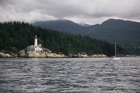 white lighthouse near coast under cloudy daytime sky thumbnail