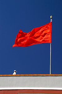 red flag waving pole under blue sky thumbnail