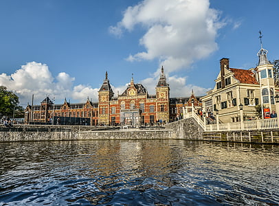 brown and white brick building facing body of water under partially cloudy skies thumbnail
