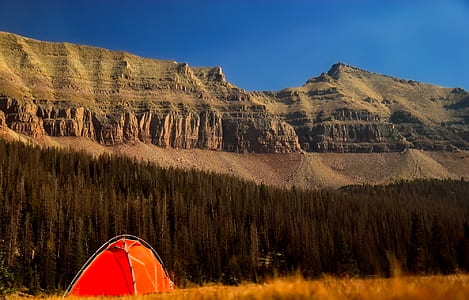 orange tent behind mountains under blue sky thumbnail
