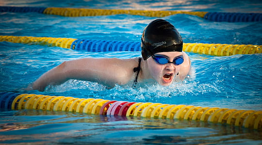 person wearing black swim cap and blue goggles thumbnail