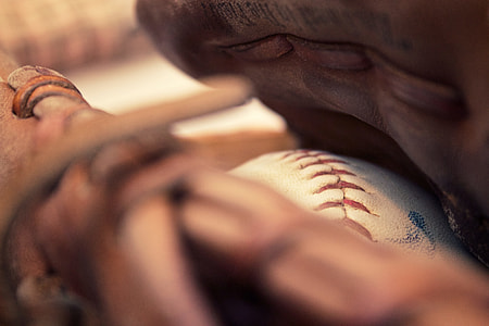 white baseball in brown leather baseball mitt closeup photography thumbnail