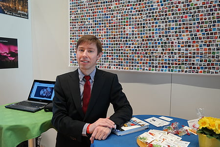 man in black formal coat standing near black laptop computer on green table thumbnail