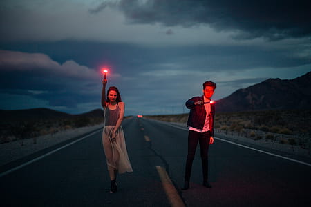 two man and man holding lights standing on concrete road thumbnail