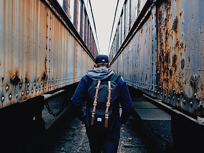 person walking between trains during daytime thumbnail