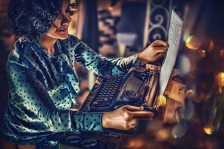 woman with black hair in blue polka-dot long-sleeved blouse holding a paper with black typewriter thumbnail